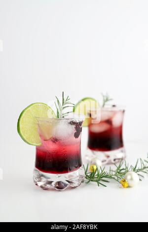 Weihnachten trinken. Nahaufnahme von zwei Glas Granatapfel Weihnachten Cocktail mit Sekt, Limonen und Rosmarin. Stockfoto