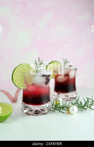 Weihnachten trinken. Nahaufnahme von zwei Glas Granatapfel Weihnachten Cocktail mit Sekt, Limonen und Rosmarin. Stockfoto