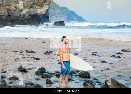 Eine junge männliche Surfer an der pazifischen Küste Strand in El Salvador, Mittelamerika Stockfoto