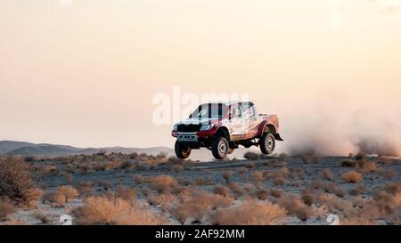 zahedan, baluchestan-iran- juli 27 2021 toyota Hulux dakar Rallye-Edition sprang in die Luft und spritzte Staub zurück bei Sonnenuntergang in Dasht e lut Wüste Stockfoto