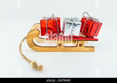 Makroökonomische Bild der hölzernen Schlitten mit einem roten Sitz mit zwei roten und einem Silber verpackte Geschenk, auf einem weißen Hintergrund. Stockfoto