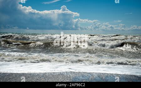 Stürmischen Himmel und welliges Meer mit Wellen schlagen der am Ufer des Meeres voll mit schönen und bunten Steinchen. Stockfoto