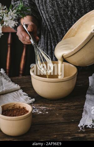 Eine Frau kochen Eine Bundt cake in eine rustikale Küche, auf einem Holztisch. Stockfoto