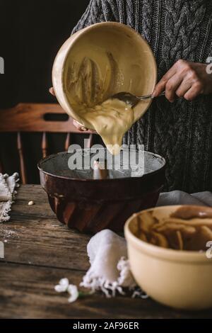 Eine Frau kochen Eine Bundt cake in eine rustikale Küche, auf einem Holztisch. Stockfoto