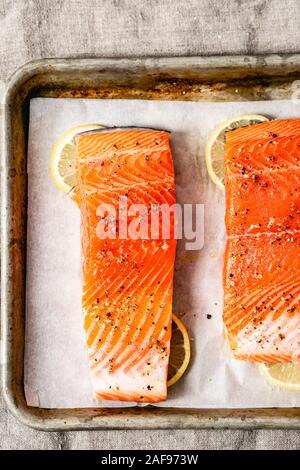 Frischer Lachs in einem Backblech, bereit für den Backofen, mit Zitronenscheiben. Stockfoto