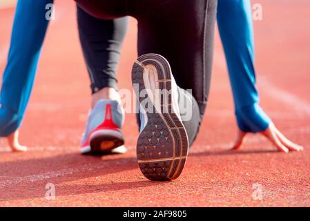 Rückansicht eines Athleten erhalten für das Rennen auf einem laufenden Track bereit. Fokus auf Schuh eines Athleten zu einem Rennen im Stadion. Stockfoto