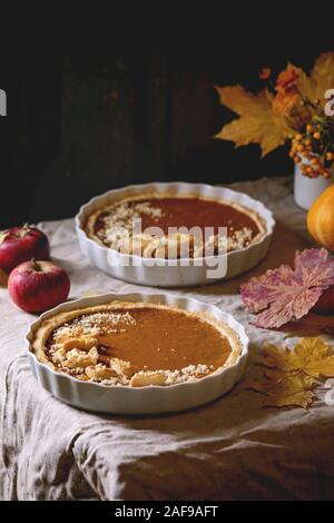 Traditionelle hausgemachte Herbst Kürbis Kuchen für Thanksgiving oder Halloween Dinner serviert in Keramik Schüssel mit gelben Blätter im Herbst, Kürbis und Äpfel auf Stockfoto