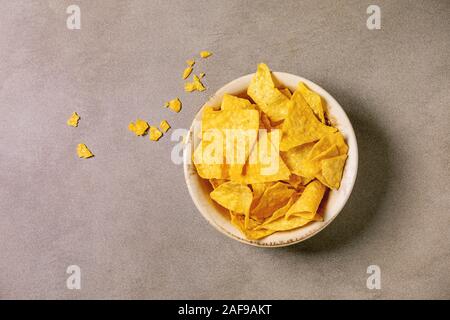 Tortilla nachos Mais Chips in Keramik Schüssel über braune Textur Hintergrund. Flach, Raum Stockfoto