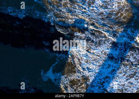 Wellen schlagen gegen die felsige Küste von St Andrews Scotland. Perfektes abstraktes Hintergrundbild. Stockfoto
