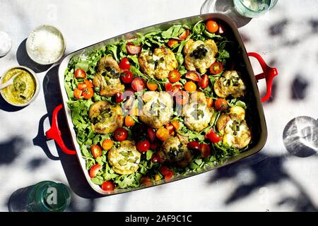 Roasted Poblano Pesto zertrümmerte Kartoffeln serviert auf einem Bett von Rucola und Tomaten Stockfoto