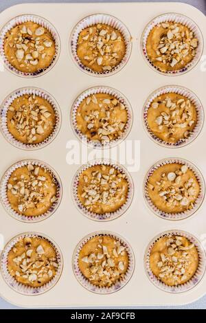 Pumpkin muffin Teig in Muffin gegossen Pan mit gehackten gerösteten Erdnüssen gekrönt. Stockfoto