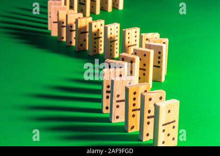 Eine geschwungene Linie von stehendem Holz- Domino auf Grün wird gesehen von Rechts beleuchtet, wodurch lange Schatten fallen auf der linken Seite. Die domino Show ist re Stockfoto