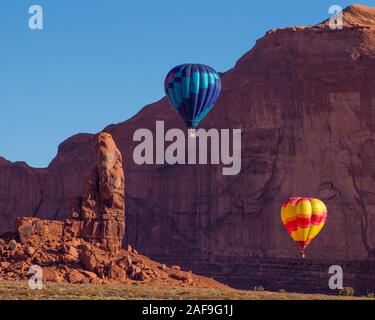 Zwei Heißluftballons fliegen im Monument Valley Ballon Festival im Monument Valley Navajo Tribal Park in Arizona. Im Vordergrund links ist. Stockfoto