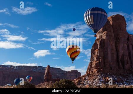 Heißluftballone fliegen durch die Daumen und Camel Butte im Monument Valley Ballon Festival im Monument Valley Navajo Tribal Park in Arizona. Stockfoto