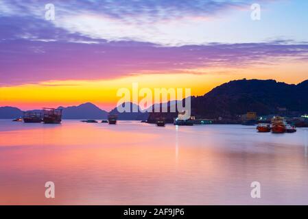 Einzigartige sonnenuntergang himmel in Vietnam Cat Ba Bucht mit schwimmenden Fischen Boot Dorf am Meer, cloudscape tropische Wetter, Langzeitbelichtung Bewegung verwischt. Stockfoto