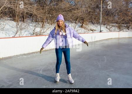 Reizende junge Frau, Schlittschuhe auf der Eisbahn. Stockfoto