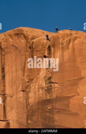 Ein BASE jumper Sprünge von der Spitze des 400-Fuß vertikale Teilfläche der Tombstone in der Kane Springs Canyon in der Nähe von Moab, Utah. Hinweis seinen Schatten auf die Klippe. Stockfoto