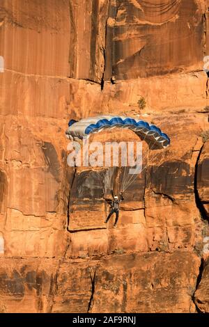 Ein Base Jumper fällt in seinem Fallschirm aus der 400-Fuß vertikale Teilfläche der Tombstone in der Kane Springs Canyon in der Nähe von Moab, Utah. Stockfoto