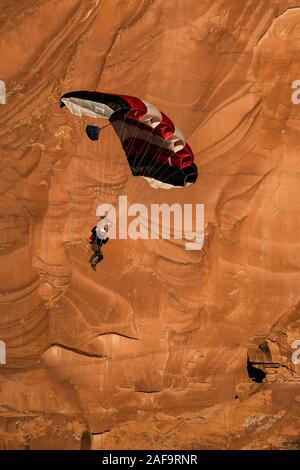 Ein Base Jumper fällt in seinem Fallschirm aus der 400-Fuß vertikale Teilfläche der Tombstone in der Kane Springs Canyon in der Nähe von Moab, Utah. Stockfoto