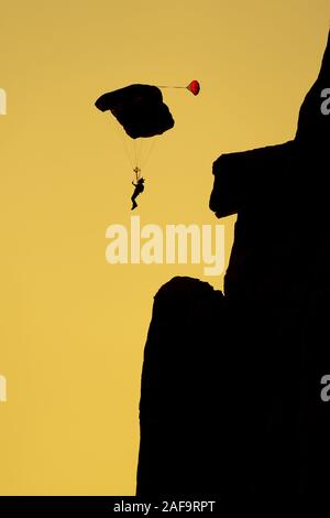 Die Silhouette einer Base Jumper Fallschirmspringen in der Kane Springs Canyon in der Nähe von Moab, Utah bei Sonnenuntergang. Stockfoto