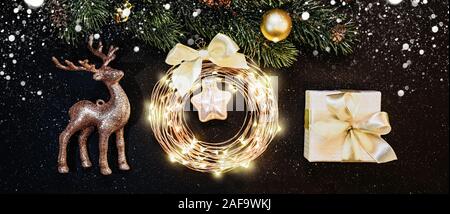 Weihnachten und neues Jahr Dekorationen auf dunklem Hintergrund: Weihnachtsbaum, Gold Dekorationen, Rentier, Garland, Geschenk Stockfoto