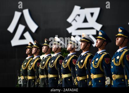 (191214) - Peking, Dez. 14, 2019 (Xinhua) - Foto am Dez. 13, 2019 zeigt die nationalen Gedenkfeier für die Opfer der Nanjing Massaker an der Memorial Hall der Opfer des Massakers von Nanjing durch die Japanischen Invasoren in Nanjing, der Hauptstadt der Provinz Jiangsu im Osten Chinas. Vor der Masse in Schwarz, Chinas nationale Flagge flog auf Halbmast als die Nation einer Trauerfeier Freitag statt der 300.000 Opfer des Massakers von Nanjing zu trauern. Fixieren eine weiße Blume, mehr als 8.000 Menschen aus allen Gesellschaftsschichten der Sechsten nationalen Trauerfeier nahmen in Nanjing, Osten Chinas Jiangs Stockfoto