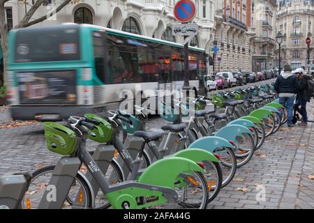 Ein Bus fährt eine Velib Bike Station in Paris. Die grüne pedal Fahrräder sind häufig durch Paris und Teil einer großen öffentlichen Fahrrad sharing System Stockfoto