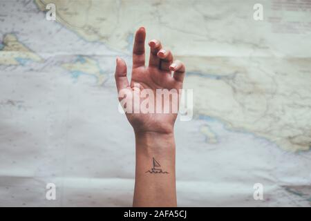 Kleines Segelboot Tattoo auf der weiblichen Knöchel. Reisen, touristische Konzept Stockfoto