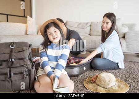 Gerne asiatische Familie bereitet sich auf Reisen zu Hause. Mutter Tochter und Vater sind packen die Koffer für die Reise. Stockfoto