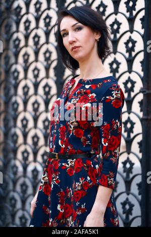 Schöne elegante Frau in der Nähe von Black posing schmiedeeisernen Toren Stockfoto