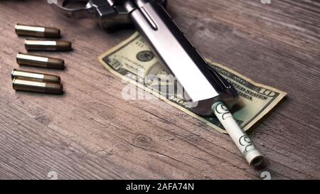 Eine Pistole mit Munition und Geld Dollar liegt auf dem Tisch. Revolver close-up. Stockfoto