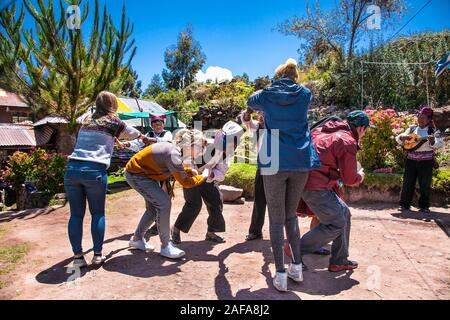 Taquile, Peru - Jan 5, 2019: Unbekannter Touristen und einheimischen Menschen in traditionellen Outfit für die Insel Taquile tanzen in Taquile Stockfoto