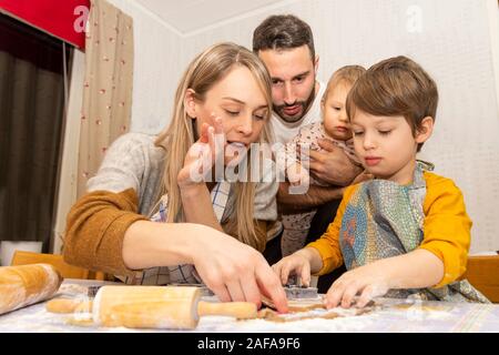 Junge Familie mit zwei Kindern, die Lebkuchen Cookies in der Küche für Weihnachten, Bild aus dem Norden von Schweden. Stockfoto