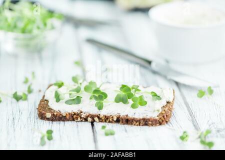 Scheibe Vollkornbrot mit frisch geschnittenen Kresse und Frischkäse auf einem alten Holztisch (selektive Fokus, Nahaufnahme) Stockfoto