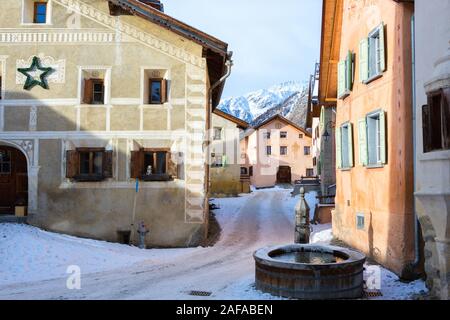 Gewundenen Straße mit typischen Häuser und Brunnen im älteren Teil von Guarda, Inn Bezirk, Kanton Graubünden, Schweiz. Stockfoto