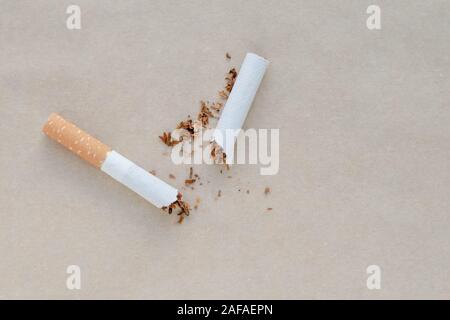 Eine zerbrochene Zigarette auf einem Hellbraunen Papier Hintergrund. Zerstreut Tabak. Kopieren, text Raum. Schlechte Gewohnheit. Sagen Sie Nein zur Sucht. Gesunder Lebensstil Konzept Stockfoto