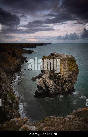 Moody Himmel über der Bucht von Wasser mit Meer Stapel auf dramatische Küste von Pembrokeshire, South Wales, UK. Majestic Marine und schroffen felsigen Küste mit Felsen. Stockfoto