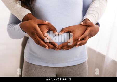 Mann die Hände auf schwangeren Bauch in Herzform Stockfoto