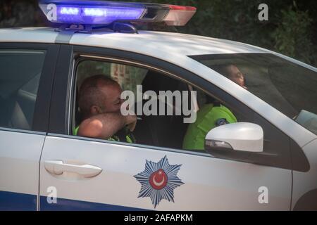 Ein türkischer Polizist genießt eine Zigarette in einem Streifenwagen der Polizei Stockfoto