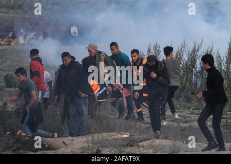 Dezember 13, 2019: Gaza, Palästina. 13. Dezember 2019. Palästinensische Demonstranten Zusammentreffen mit den israelischen Streitkräften im Osten der al Bereij Flüchtlingslager im zentralen Gazastreifen, während dieser Freitag große März wieder Proteste. Demonstranten hatten an der Grenze gesammelt, mit einigen warfen Steine gegen israelische Soldaten auf der anderen Seite der Trennungsmauer stationiert. Die israelischen Streitkräfte feuerte Tränengas und scharfer Munition auf die Demonstranten wurden verletzt, einige von ihnen. Der große Marsch der Rückkehr der Proteste an der Grenze zum Gazastreifen Am 30. März 2018 für die Aufhebung der israelischen Blockade von Anrufen Stockfoto