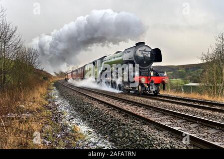 Langcliffe, in der Nähe von Settle, North Yorkshire, UK. 14 Dez, 2019. Der Flying Scotsman Dampflokomotive mit 'Dampf besondere Weihnachten Dalesman'. Hier bei Langcliffe in Richtung Norden nach Carlisle auf dem berühmten Settle Carlisle railway Linie gesehen, auf einer Rundreise von Liverpool. Der Zug einige nassen Winter Wetter mit starkem Regen und mit Hagel von der Rennstrecke gesehen werden kann. Die Rückfahrt war über Shap auf der West Coast Main Line. Quelle: John Bentley/Alamy leben Nachrichten Stockfoto