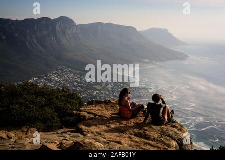 Freunde thront auf dem Gipfel von Kapstadts Lion's Head Mountain Blick über das Camp Bay Strände in Richtung Cape Point. Stockfoto