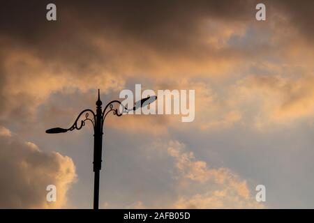 Eine Straßenlaterne auf der linken und bewölktem Himmel im Hintergrund. Stockfoto