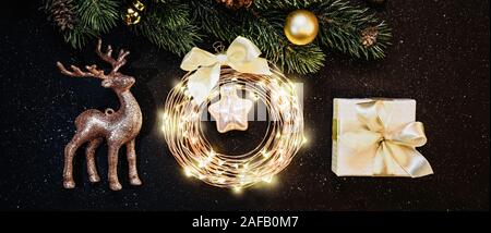 Weihnachten und neues Jahr Dekorationen auf dunklem Hintergrund: Weihnachtsbaum, Gold Dekorationen, Rentier, Garland, Geschenk Stockfoto