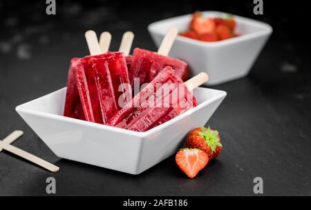 Schiefer Tafel mit hausgemachten Erdbeer Eis am Stiel (selektive Fokus, Nahaufnahme) Stockfoto