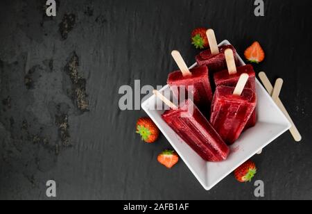 Schiefer Tafel mit hausgemachten Erdbeer Eis am Stiel (selektive Fokus, Nahaufnahme) Stockfoto