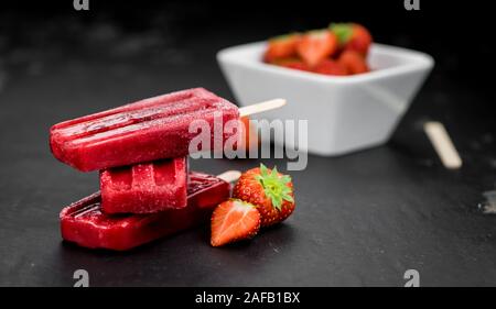 Schiefer Tafel mit hausgemachten Erdbeer Eis am Stiel (selektive Fokus, Nahaufnahme) Stockfoto