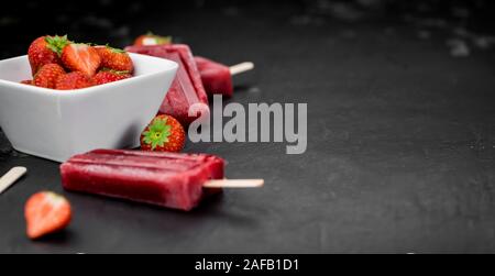 Schiefer Tafel mit hausgemachten Erdbeer Eis am Stiel (selektive Fokus, Nahaufnahme) Stockfoto