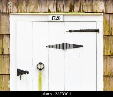 Alte hölzerne weiße Tür mit schwarzen strape Scharniere Stockfoto