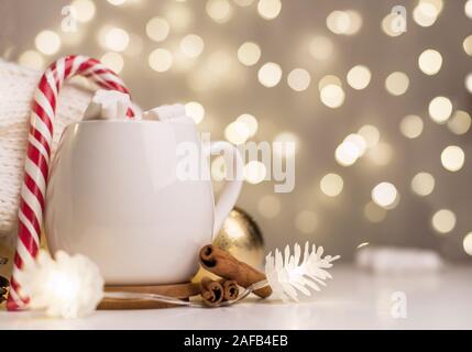 Tasse heißen Kakao mit Marshmallows und Zuckerstangen Hintergrund mit schönen Weihnachtsbeleuchtung bokeh. Kaffee. Unscharfer Hintergrund. Stockfoto